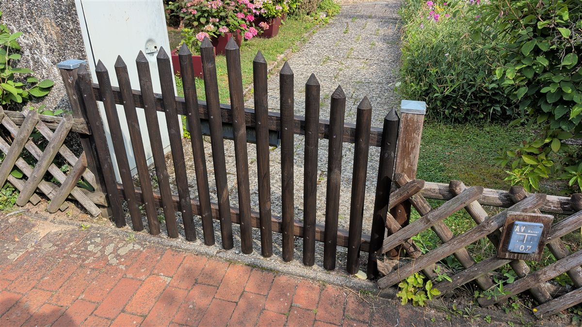 Holzzaun nach dem Einsatz: frisch dunkel gebeizt, gerade